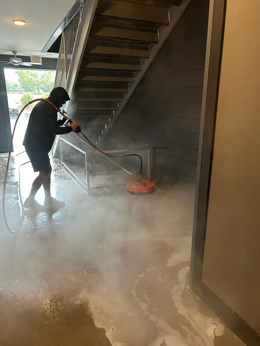 Worker using a surface cleaner on an apartment hallway floor, in-progress action shot.